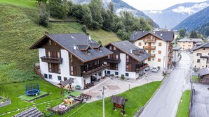 Ein Wohngebäude mit Balkon, einer kleinen Spielanlage und einer Straße davor.