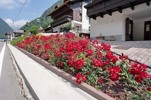 Un bâtiment doté d’un balcon, d’une enseigne et d’un parterre fleuri avec des fleurs rouges.