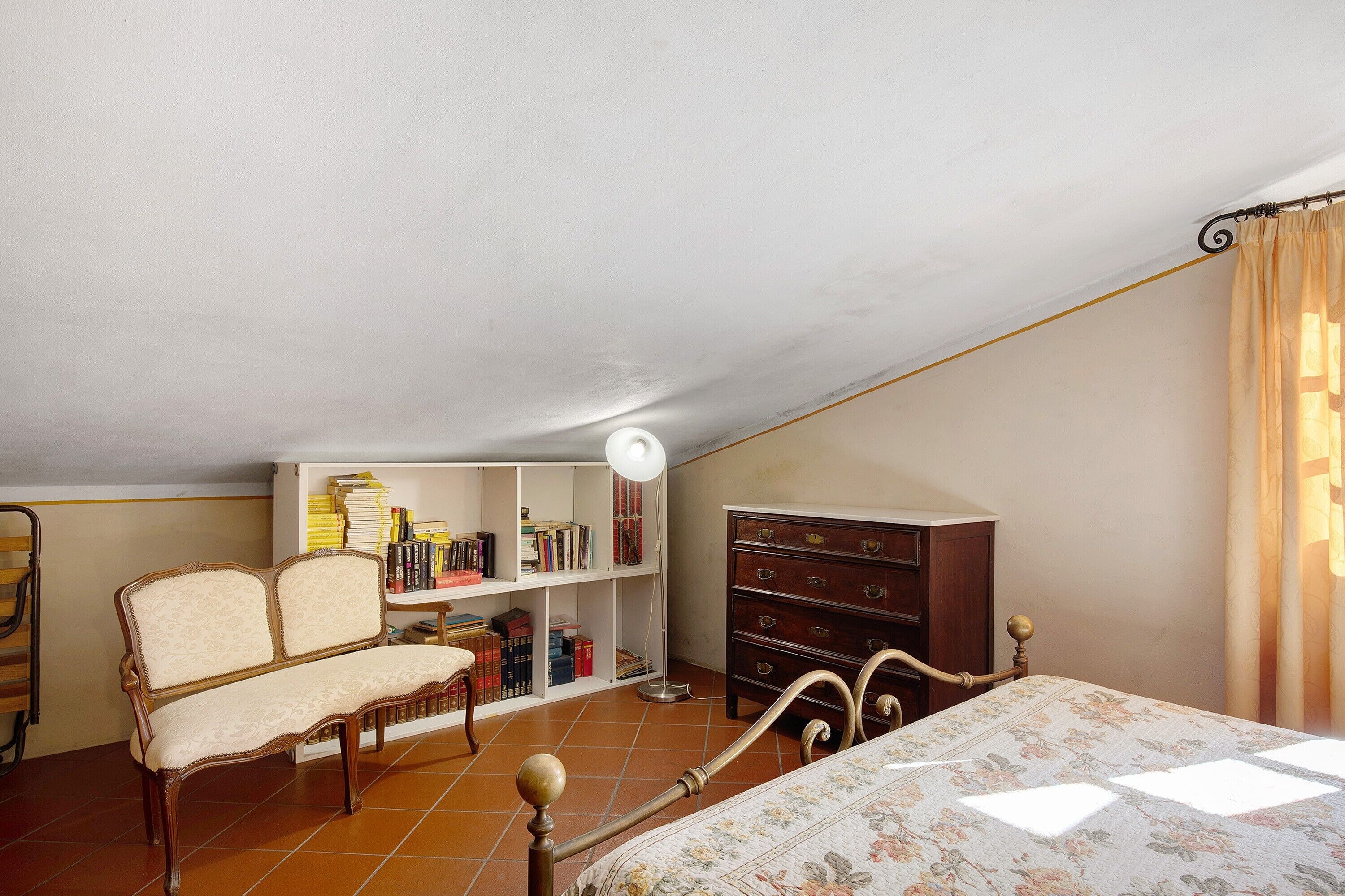 A bedroom with a bed, a wooden dresser, a bookshelf, and a chair.