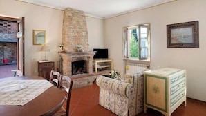 Un salon avec une cheminée, un téléviseur, une table à manger et un canapé.