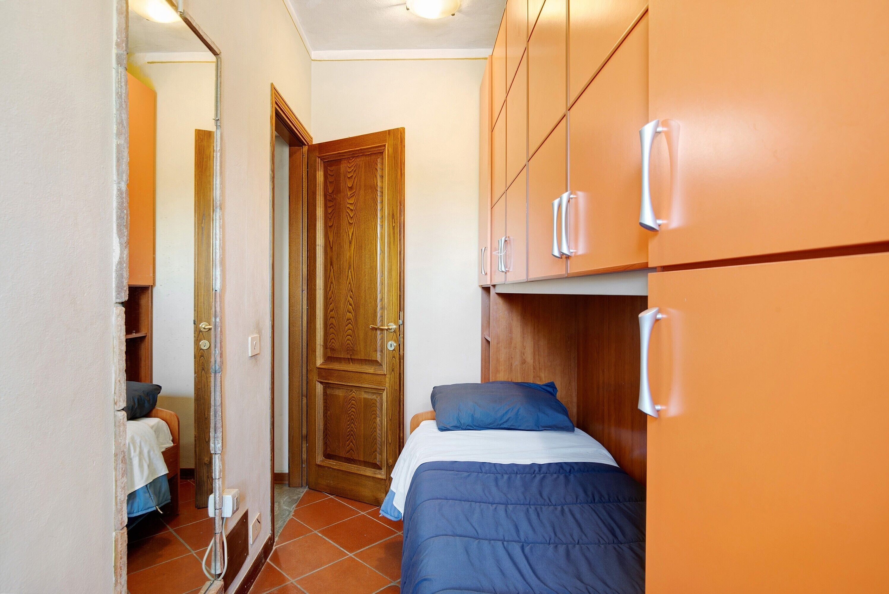 A bedroom with a bed, a wooden door, and a wardrobe.