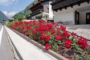 Un bâtiment doté d’un balcon, d’une enseigne et d’un parterre fleuri avec des fleurs rouges.