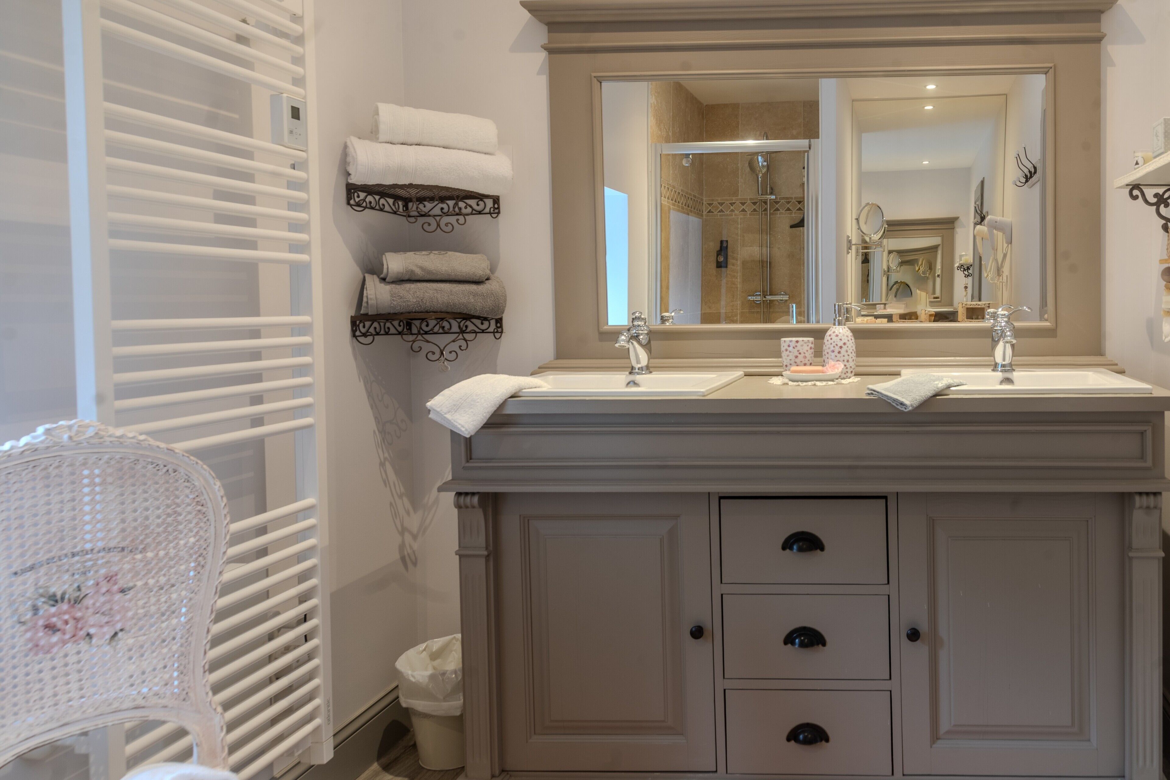 A bathroom with a double sink vanity, a large mirror, and a towel rack with neatly folded towels.