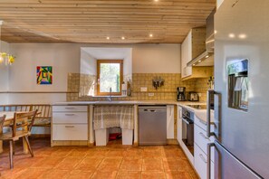 Une cuisine moderne avec un plafond en bois, un dosseret carrelé, des appareils électroménagers en acier inoxydable et une fenêtre qui laisse entrer la lumière naturelle.