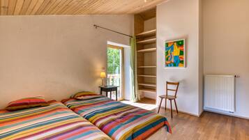 Un dormitorio con dos camas, una silla, un radiador y una ventana.