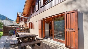 Ein Holzhaus mit einer Terrasse, einem Tisch und einer Schiebetür.