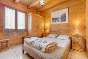 A wooden bedroom with a bed, nightstands, a dresser, and a painting on the wall.