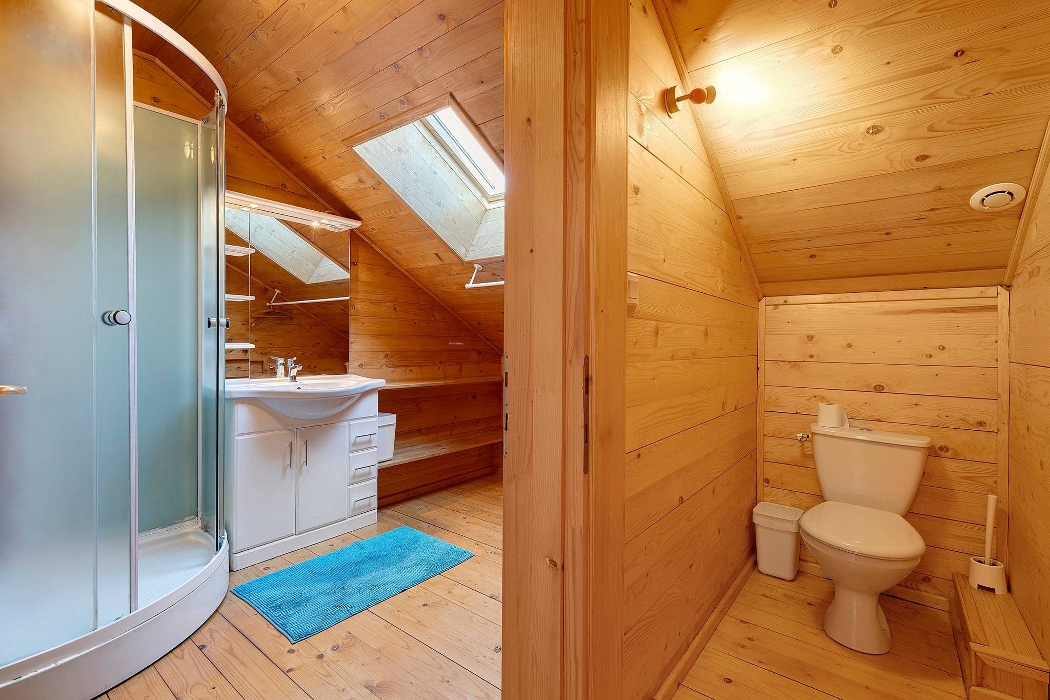 Une cabane en bois dotée d’une salle de bain comprenant des toilettes, un lavabo et une douche.