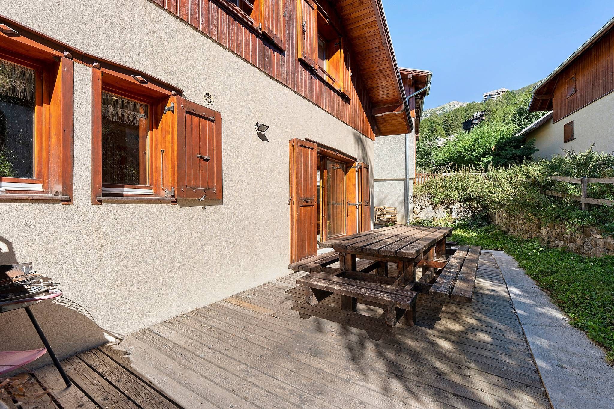 Una terraza de madera con mesa de picnic y zona de parrilla.
