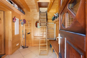 Interior em madeira com escada central, quadro branco e materiais de limpeza.
