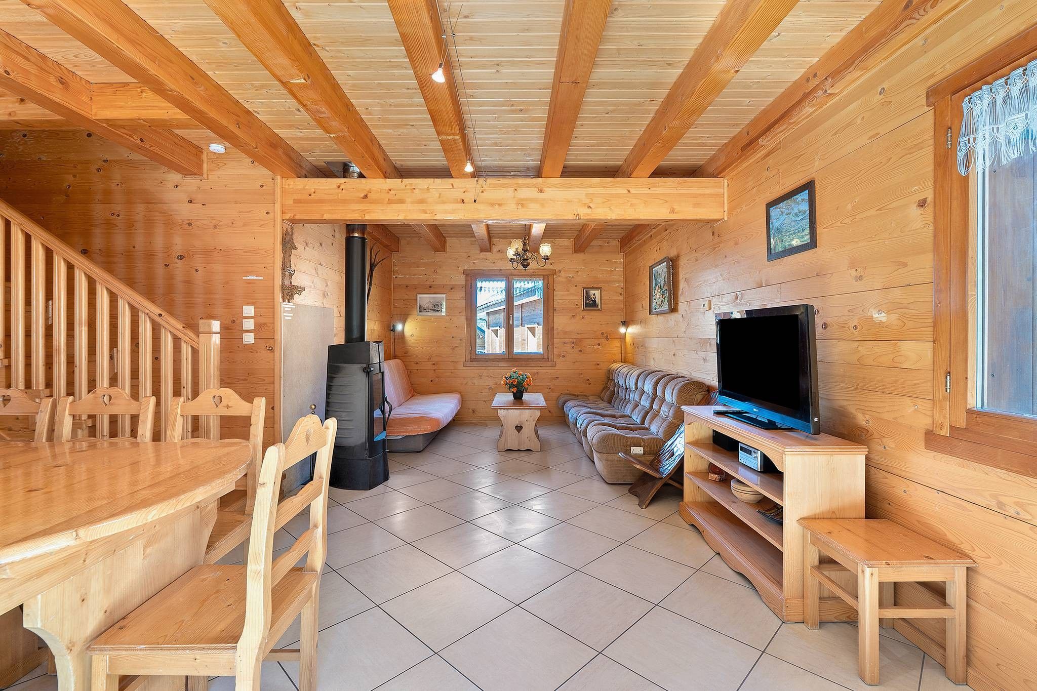 Ein Holzblockhaus-Interieur mit Essbereich, Sitzgelegenheiten, Kamin und Fernseher.