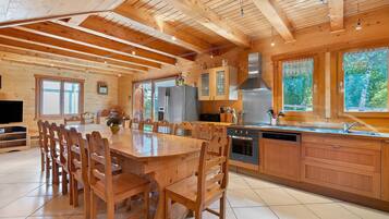 Une cuisine spacieuse dotée de meubles en bois, d’une hotte en acier inoxydable et d’un grand îlot central avec des sièges.