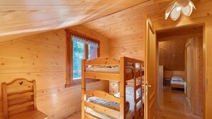 Ein Zimmer einer Holzhütte mit Etagenbetten, einem Schreibtisch und einem Fenster.
