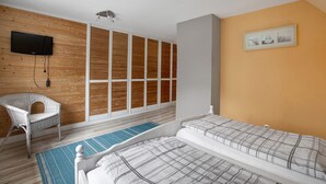 Un dormitorio con cama, una silla, un televisor y un armario.