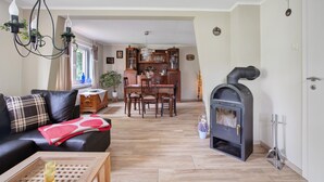 Una sala de estar con chimenea, comedor y cocina con armarios de madera.