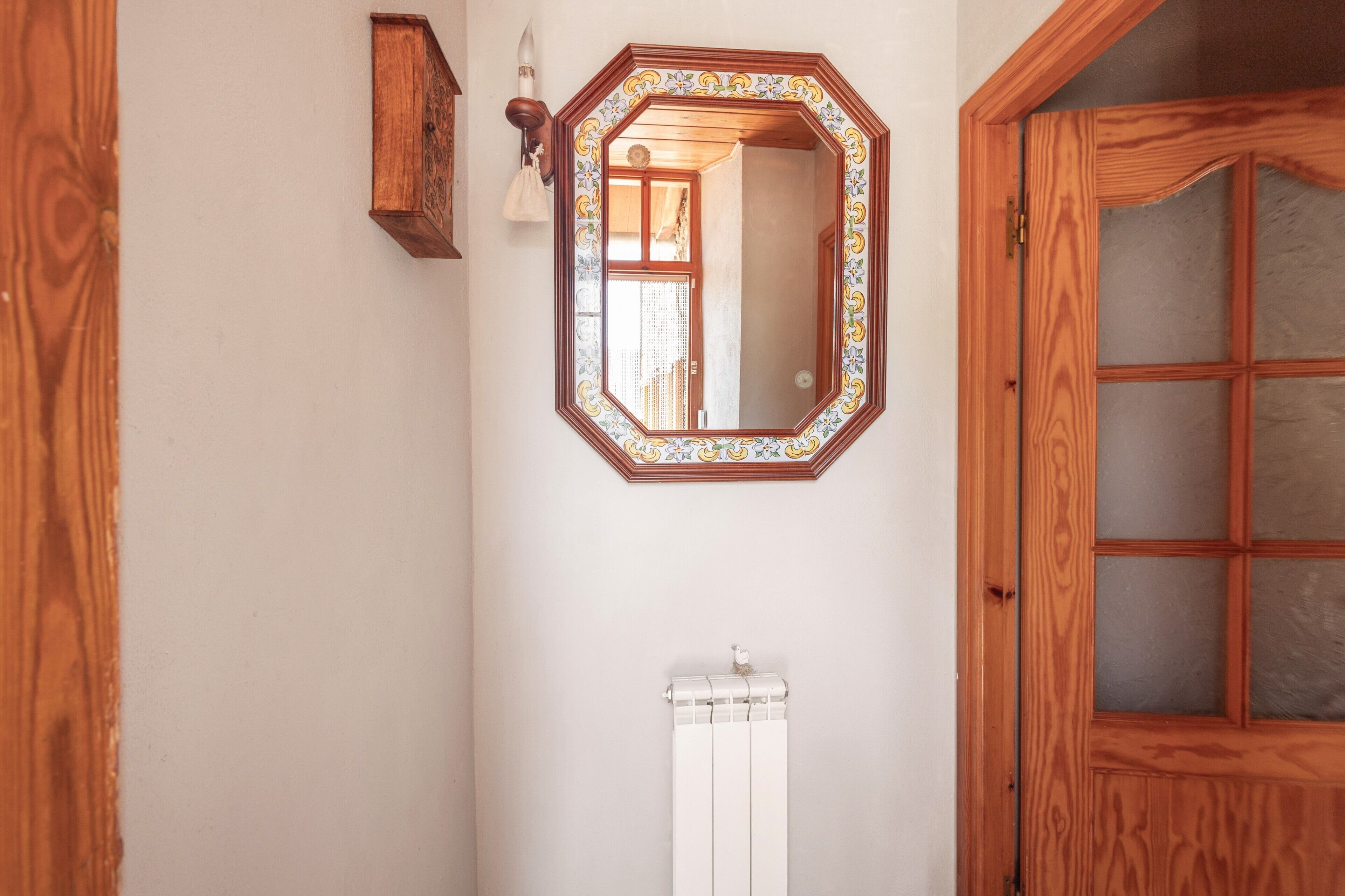 Une salle de bain avec une porte en bois, un miroir doté d’un cadre décoratif, un porte-serviettes et un radiateur.