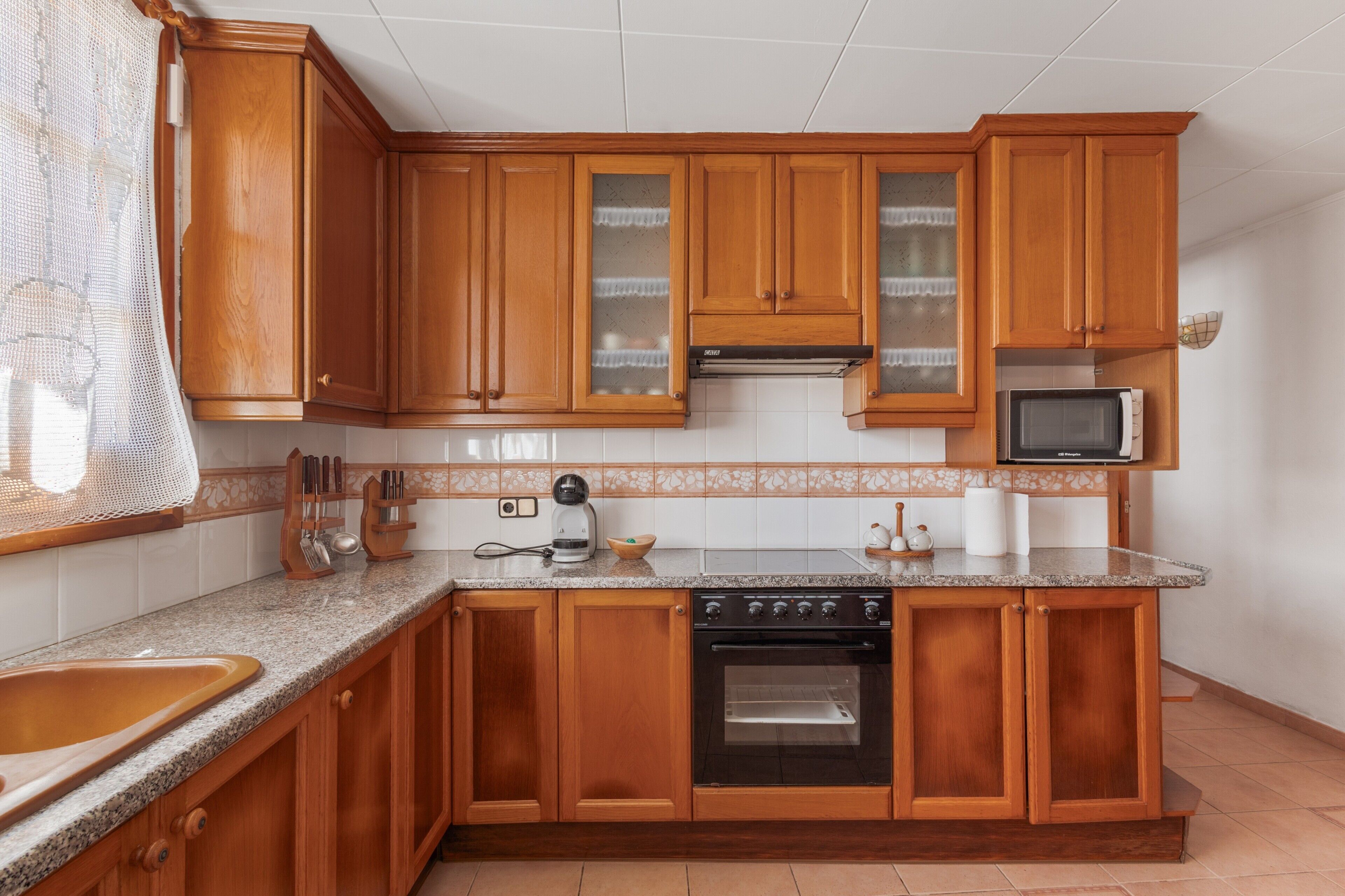 A kitchen with wooden cabinets, a microwave, an oven, and a sink.