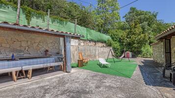 Ein Patio mit einer Steinmauer, einer Bank, einer Hängematte und einem Tisch mit kariertem Tischläufer.