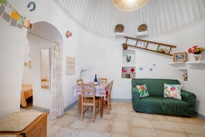 Una habitación acogedora con una mesa de comedor, sillas, un sofá verde y una pequeña escalera.
