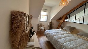 A bedroom with a sloped ceiling, a bed, a hanging light fixture, a chair, and a window. - Ocean View XXL Terrace – Premium (Pornic)