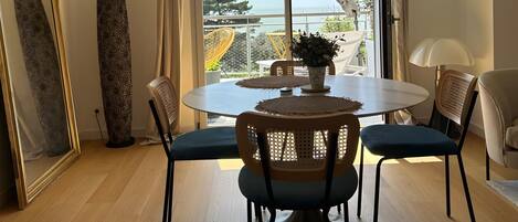 Un comedor con una mesa redonda, sillas y vistas al exterior a través de un ventanal grande.