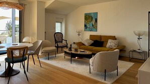 A modern living room with a sofa, chairs, a coffee table, and a painting on the wall. - Ocean View XXL Terrace – Premium (Pornic)