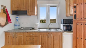 Una cocina con armarios de madera, una encimera, un fregadero, una ventana y un microondas.