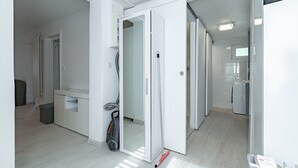 Un intérieur moderne avec un couloir menant à une cuisine, un aspirateur et une valise.