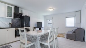 Une cuisine moderne avec des meubles blancs, un plan de travail en marbre et une table à manger avec des chaises.