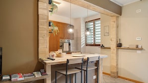 A kitchen with a wooden island, bar stools, hanging lights, and a window with blinds. - Apartment 'Typical  In Valtellina' with Mountain View, Private Terrace and Wi-Fi (Montagna In Valtellina)