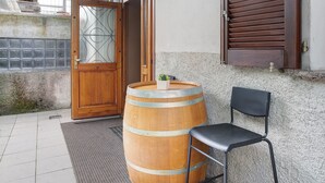 A wooden barrel, a black chair, and a wooden door with a glass panel. - Apartment 'Typical  In Valtellina' with Mountain View, Private Terrace and Wi-Fi (Montagna In Valtellina)
