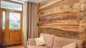 A wooden wall, a beige sofa with pillows, and a wooden door with glass panels. - Apartment 'Typical  In Valtellina' with Mountain View, Private Terrace and Wi-Fi (Montagna In Valtellina)