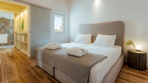 Un dormitorio con cama, mesita de noche y vistas al baño.