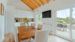 Una cocina moderna con armarios blancos, una mesa de comedor de madera y un ventanal grande.