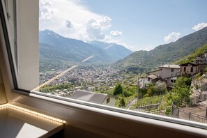 A view from a window overlooking a town with mountains in the background. - Apartment 'Leuscc' with Mountain View, Wi-Fi and Air Conditioning (Montagna In Valtellina)