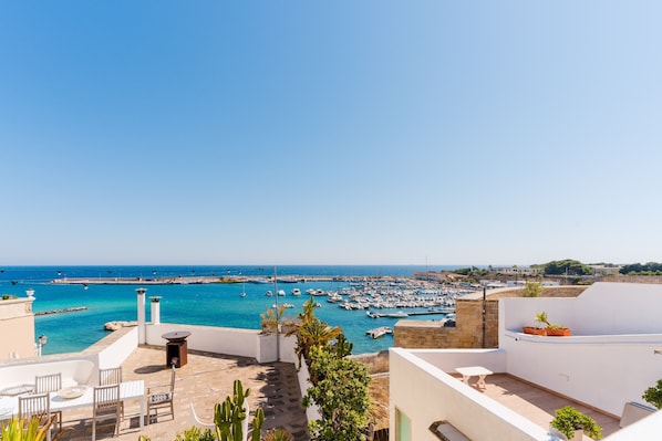 A rooftop terrace with outdoor seating, a view of the sea, and boats. - Holiday Home 'Torre Matta Otranto' with Sea View, Wi-Fi and Air Conditioning (Otranto)