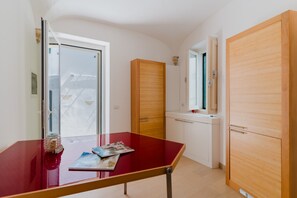Une pièce avec une table rouge, des meubles en bois, une porte blanche et une fenêtre.