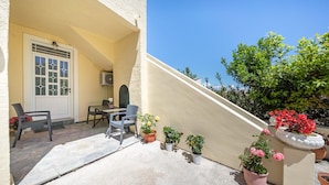 A patio with a table and chairs, potted plants, and a staircase.