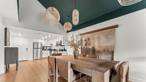 Eine moderne Küche mit weißen Schränken, Edelstahlgeräten und einem Essbereich mit einem Holztisch und Stühlen.
