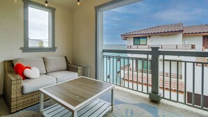 Ein Balkon mit einer Rattan-Couch, einem kleinen Tisch und Lichterketten.