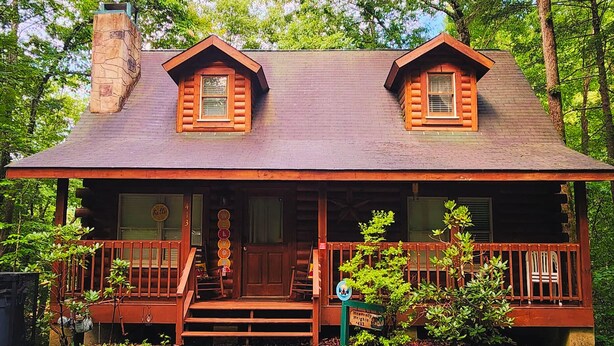 A cabin with a stone chimney, a porch with steps, and a 'Hello' sign. - Gatlinburg Resort Cabin - Hot Tub, Game Room, Sleeps 6  BOOK NOW FOR FALL COLORS (Gatlinburg)
