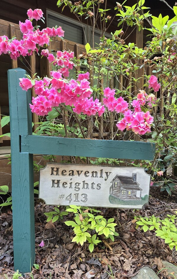 A wooden sign with a house illustration and the text "Heavenly Heights #413".