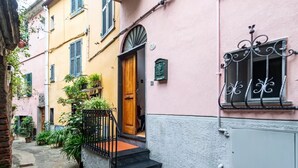 Un estrecho callejón con un edificio que presenta una puerta de madera, una pequeña escalera y una barandilla de metal.