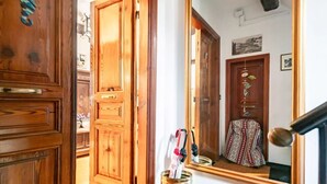 Una puerta de madera, un espejo que refleja un vestido estampado y un frasco con objetos.