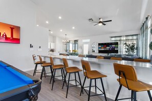 Une cuisine moderne dotée d’un îlot central, de tabourets de bar et d’une table de billard.