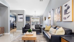 A modern living room with a sofa, coffee table, and artwork on the wall. - Fun house with Games! (North Las Vegas)