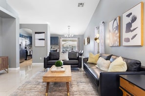 A modern living room with a sofa, coffee table, and artwork on the wall.