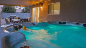 A hot tub with a waterfall feature, surrounded by a patio area with outdoor furniture. - Fun house with Games! (North Las Vegas)