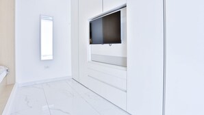 Quarto moderno com uma janela grande, paredes brancas e piso de mármore.