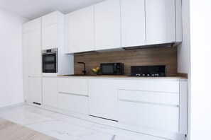 A modern kitchen with white cabinets, a microwave, and an oven.